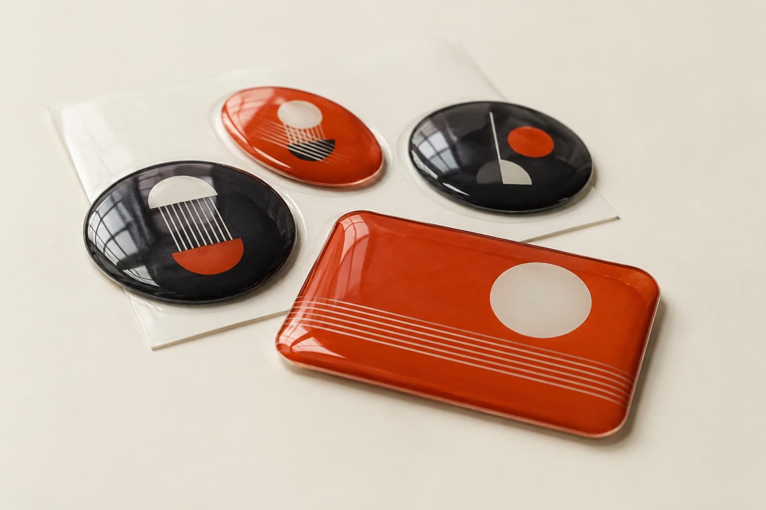 Four resin domed stickers, three round and one rectangular, in orange and charcoal, with a thick glossy dome